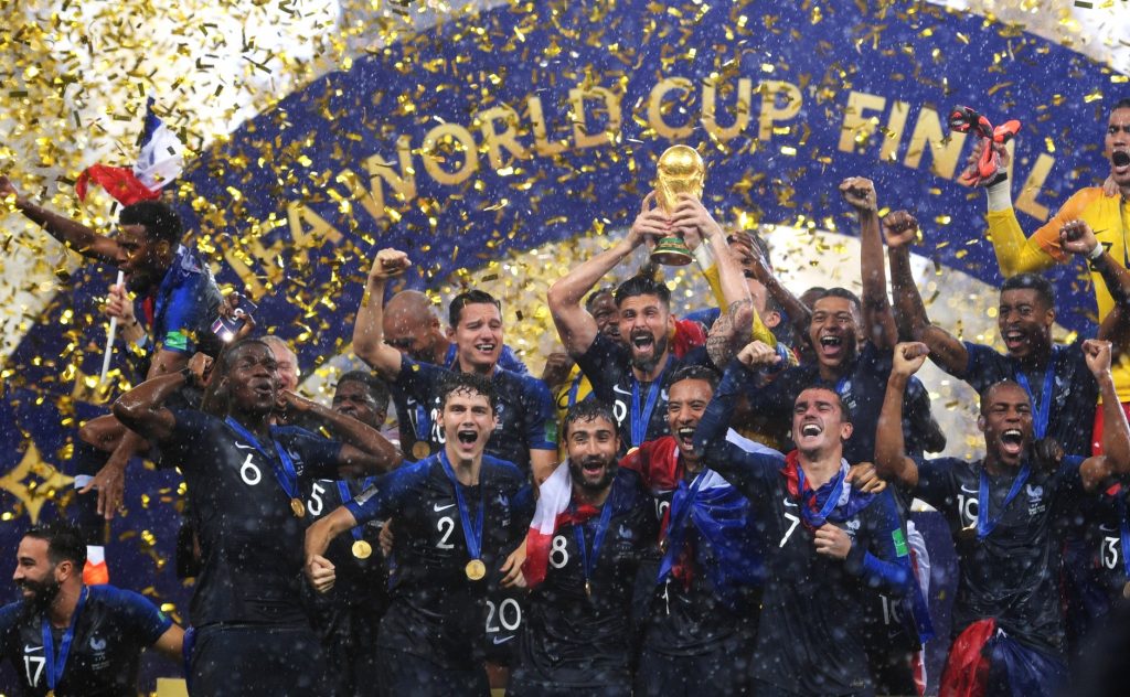 A group of men celebrate with the World Cup trophy amidst a shower of confetti