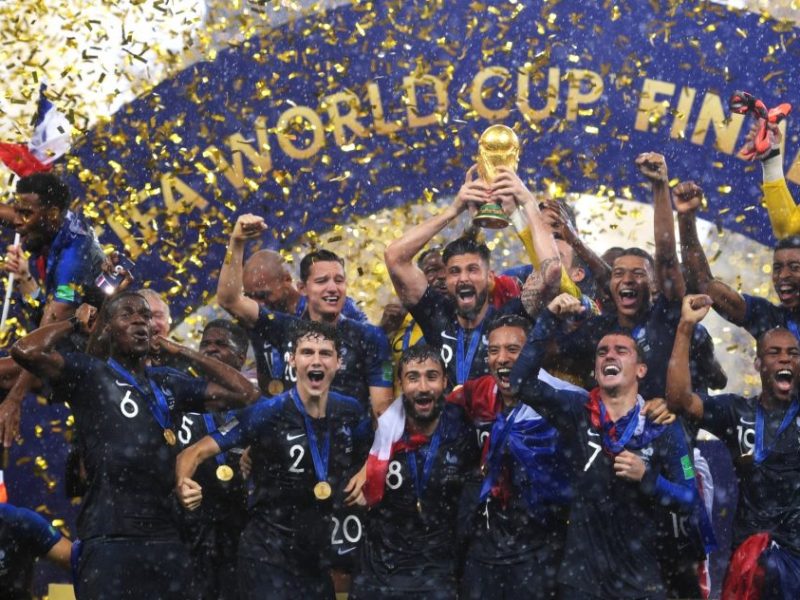 A group of men celebrate with the World Cup trophy amidst a shower of confetti