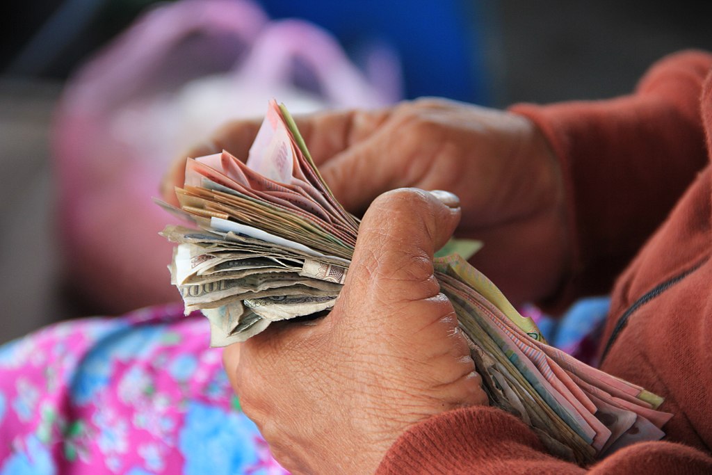 A person counts a stack of paper currency.