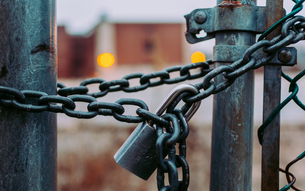A lock and chain hold a gate shut.