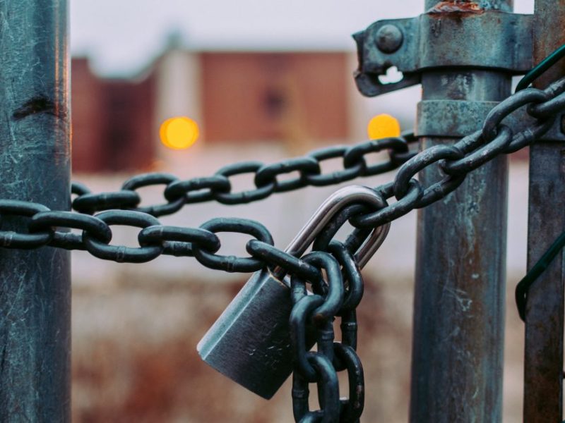 A lock and chain hold a gate shut.