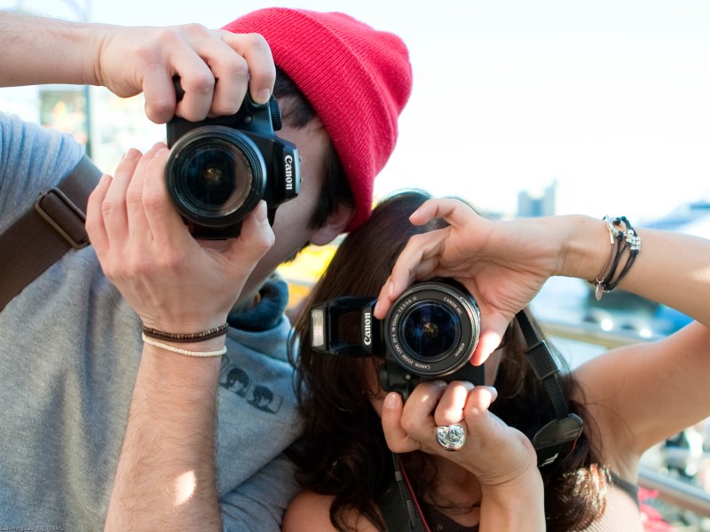 Photograph of two people holding cameras and apearing to photograph the viewer